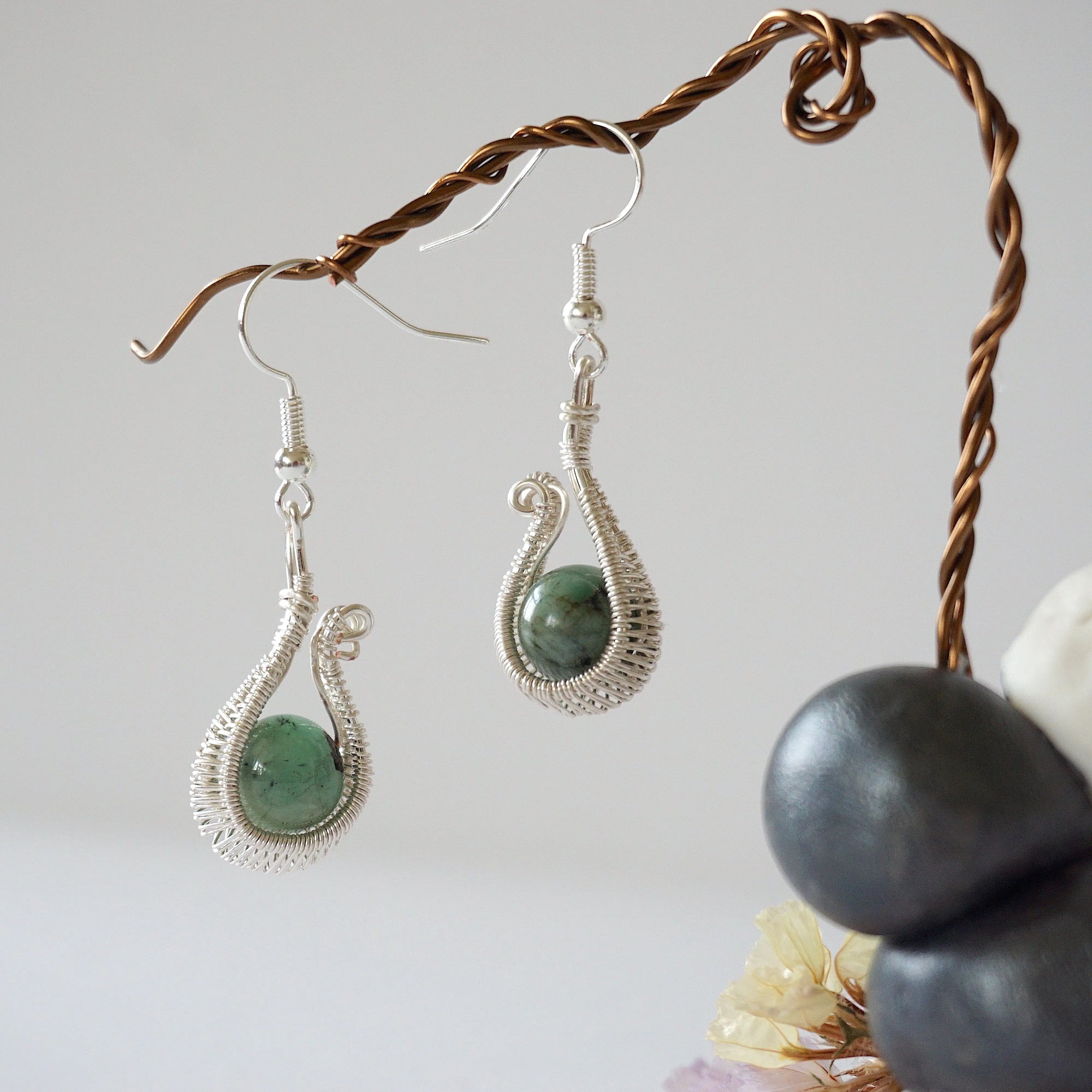 Side angle view of wire wrapped emerald drop earrings in soft silver copper with natural emerald bead and elegant drop shape