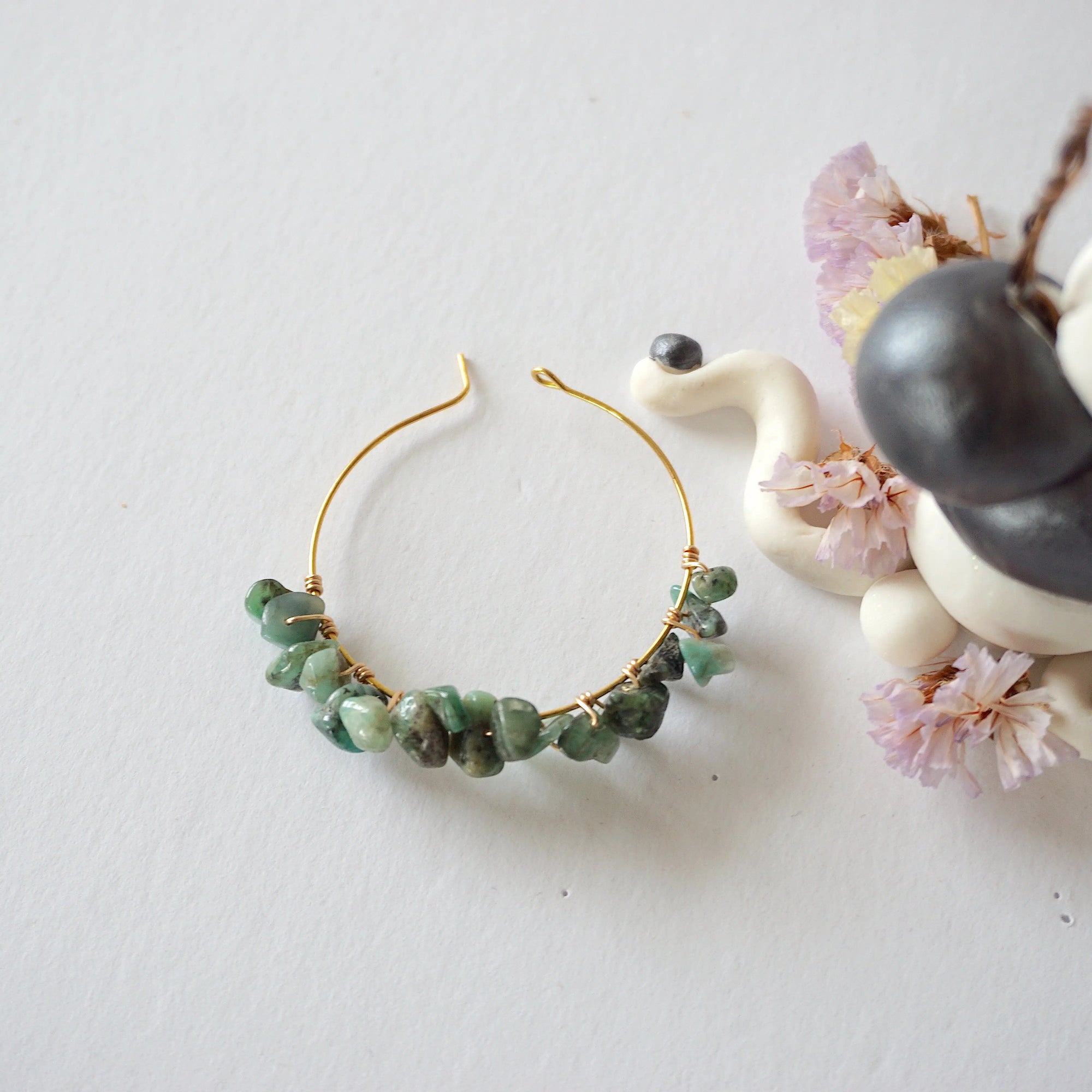 Emerald hoop earrings on flat surface showing classic hoop shape natural emerald chips and handcrafted wire wrapping