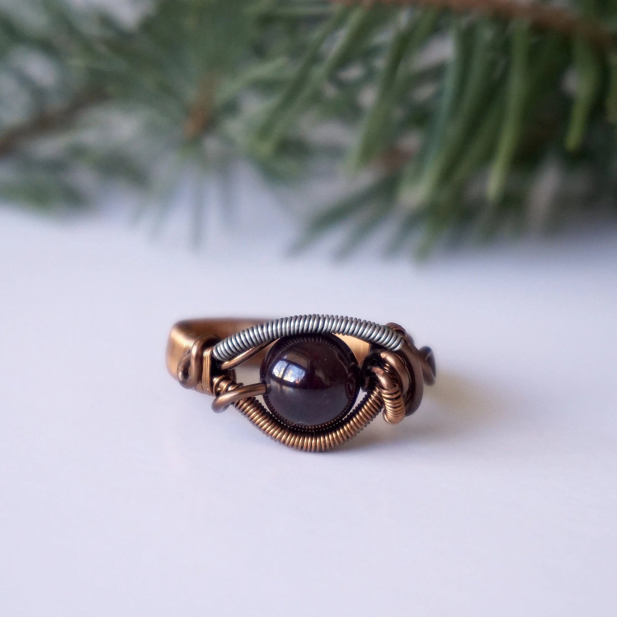 Front angle view of a wire wrapped garnet ring featuring an 8mm garnet crystal bead and mixed metal wire