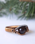 Right side angle view of a wire wrapped garnet ring highlighting the geometric mixed metal wire pattern