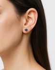 Woman wearing natural raw sapphire stud earrings with 925 sterling silver posts — handcrafted September birthstone jewelry