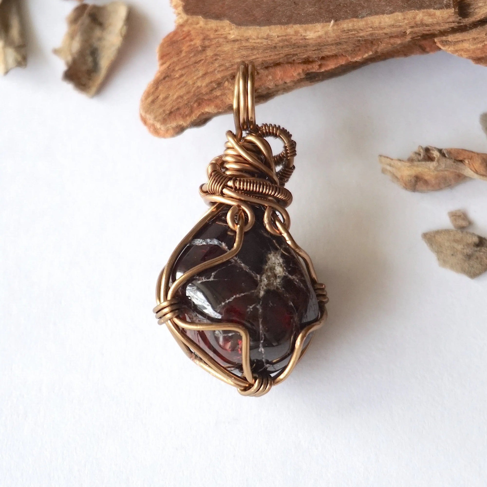 Back view of a women’s garnet wire wrapped pendant necklace in antique bronze copper, showing the detailed handcrafted wire wrapping