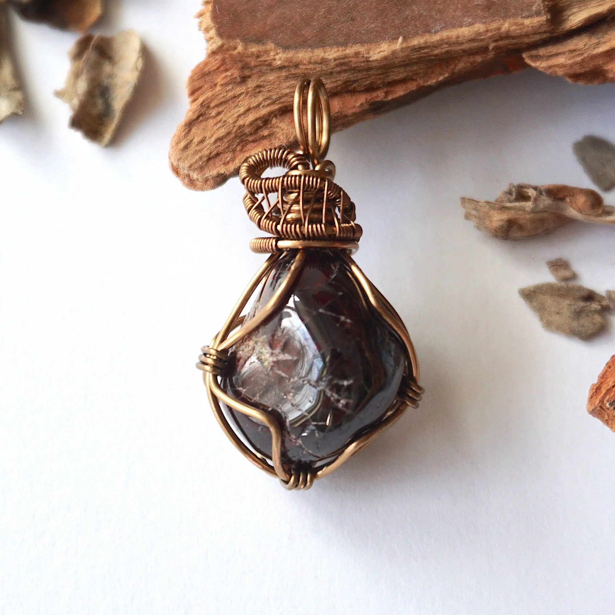 Front angle view of a women’s garnet wire wrapped pendant in antique bronze copper, showcasing the natural garnet and handcrafted wire work