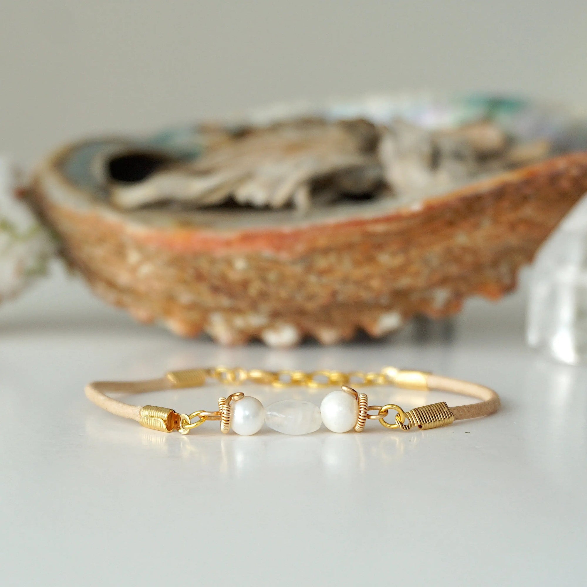 Front view of a women’s pearl and moonstone leather bracelet with freshwater pearls and rainbow moonstone centerpiece