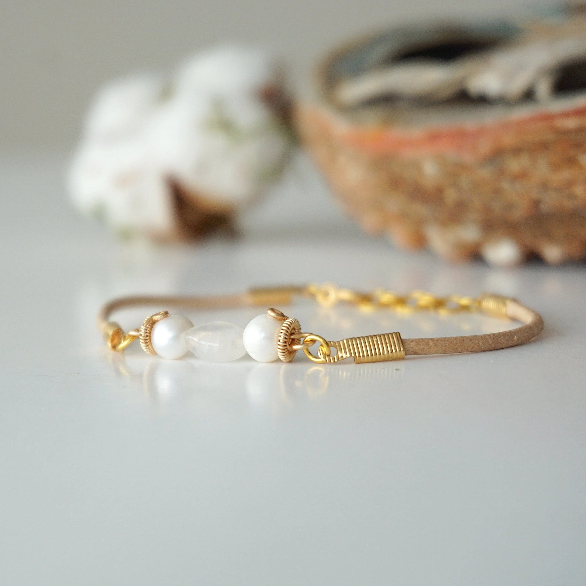 Side view of a women’s pearl and moonstone leather bracelet showing gold plated wire wrapping and leather strap