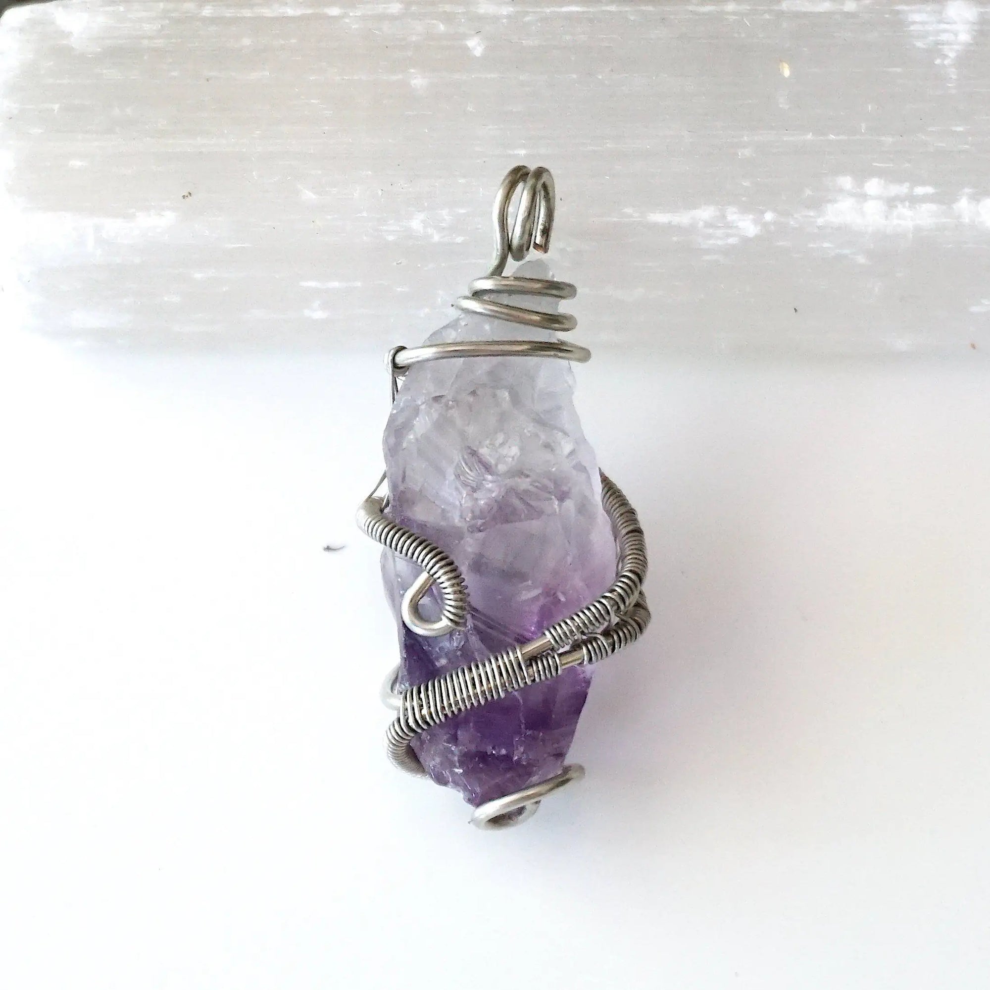 Back side angle of women’s raw amethyst pendant necklace wire wrapped in white gold plated copper