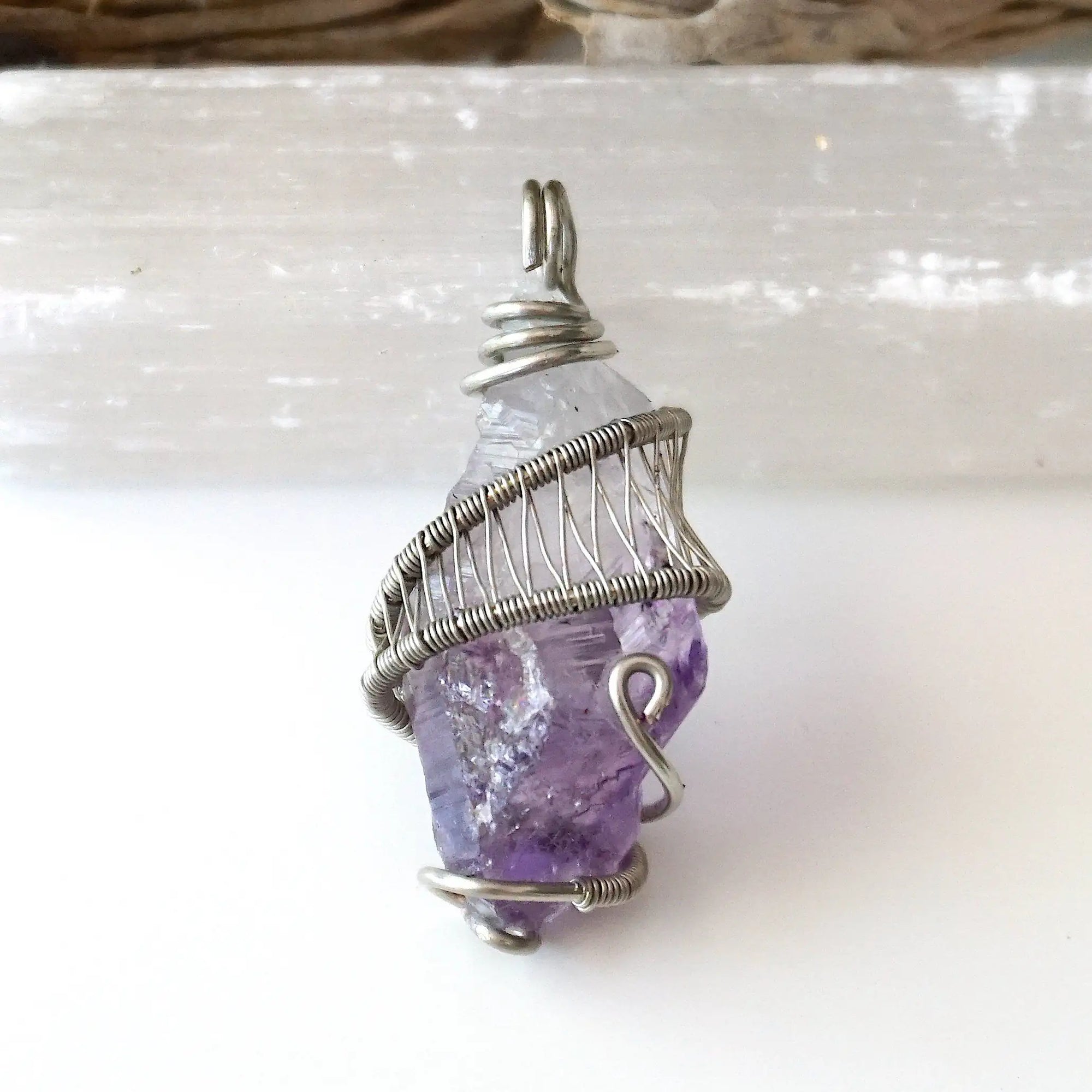 Detailed front view of women’s raw amethyst pendant wire wrapped in white gold plated copper