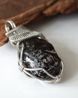 Right angle close-up of apache tears obsidian pendant – highlighting unique wire-wrapped artistry, volcanic glass, inclusive jewelry.