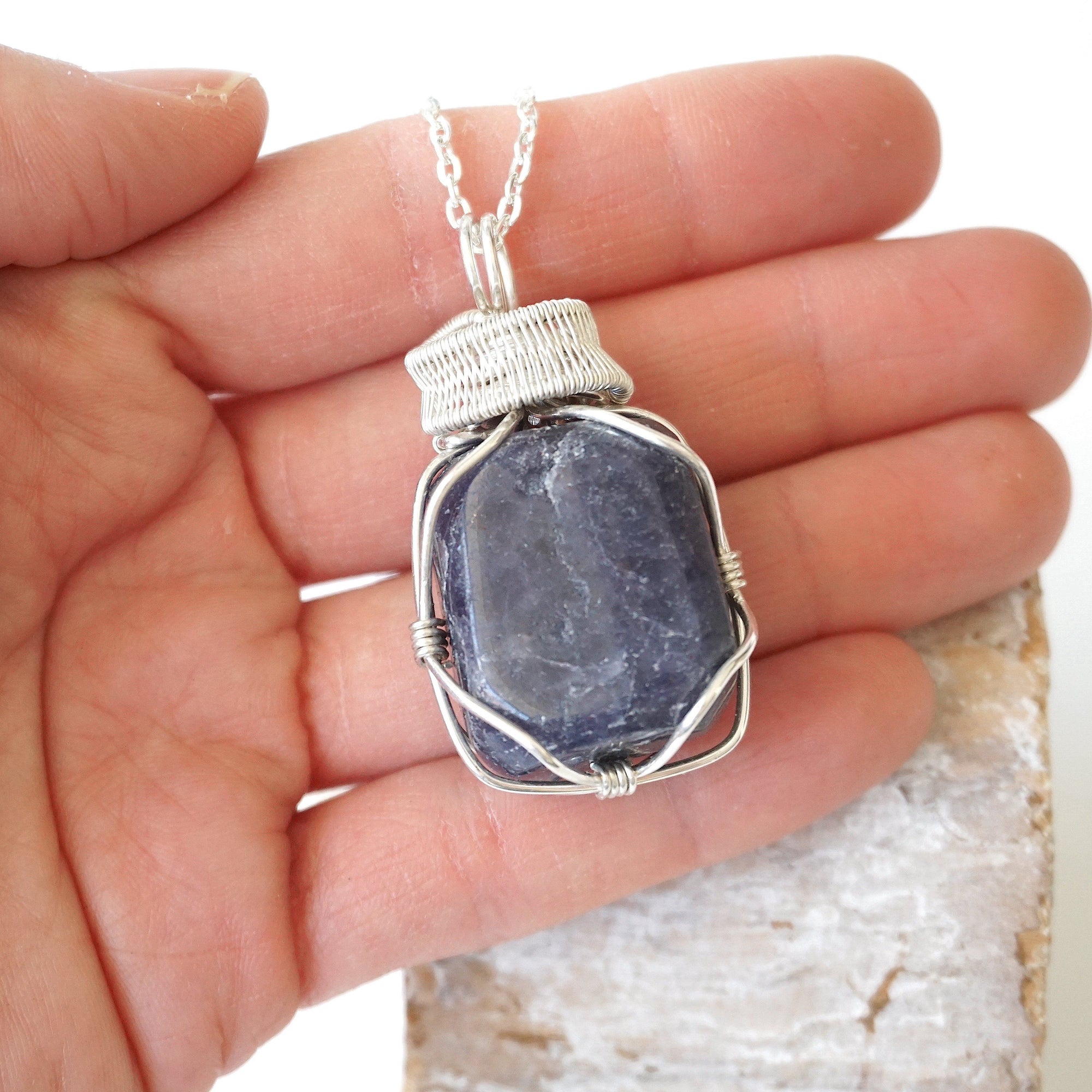 Sapphire necklace for men in hand for size reference – polished raw sapphire, 925 sterling silver wire, September birthstone, masculine design.