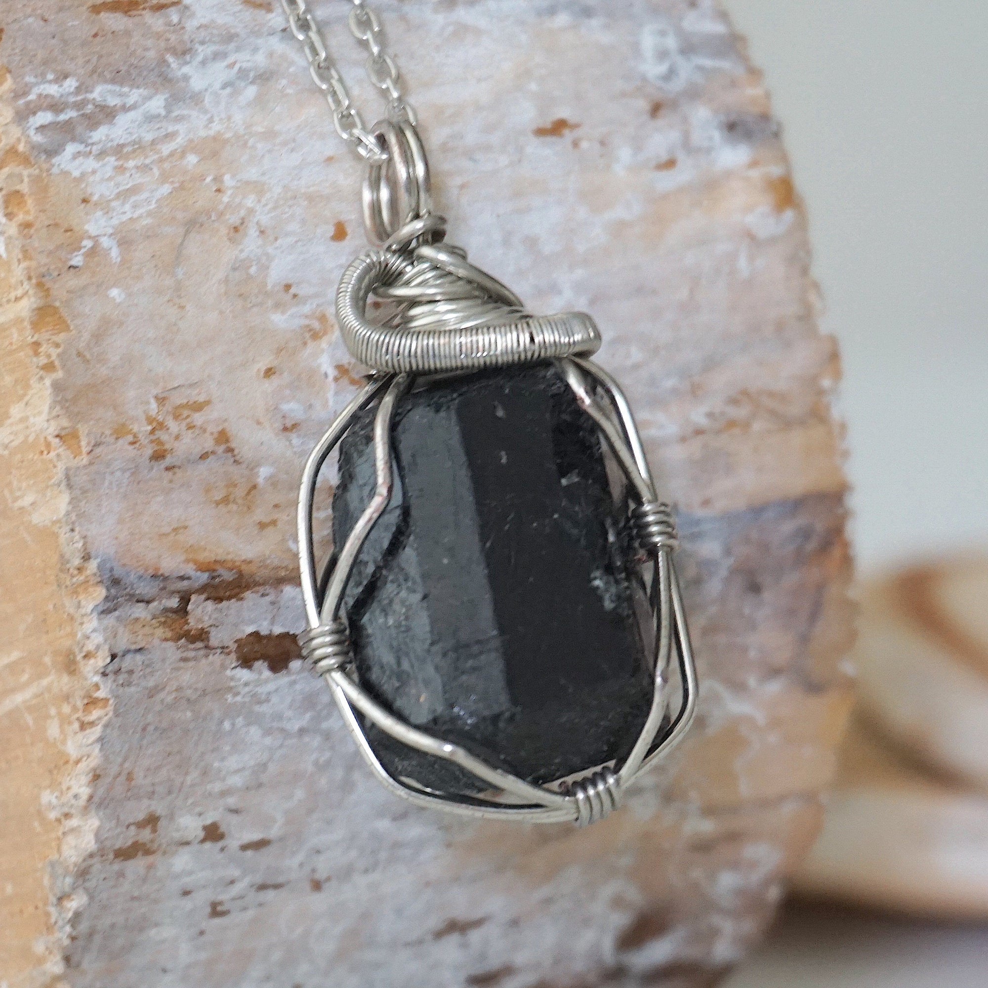 Right angle detail of raw black tourmaline necklace for men – highlights artisan dark silver copper wire wrapping and bold stone texture.