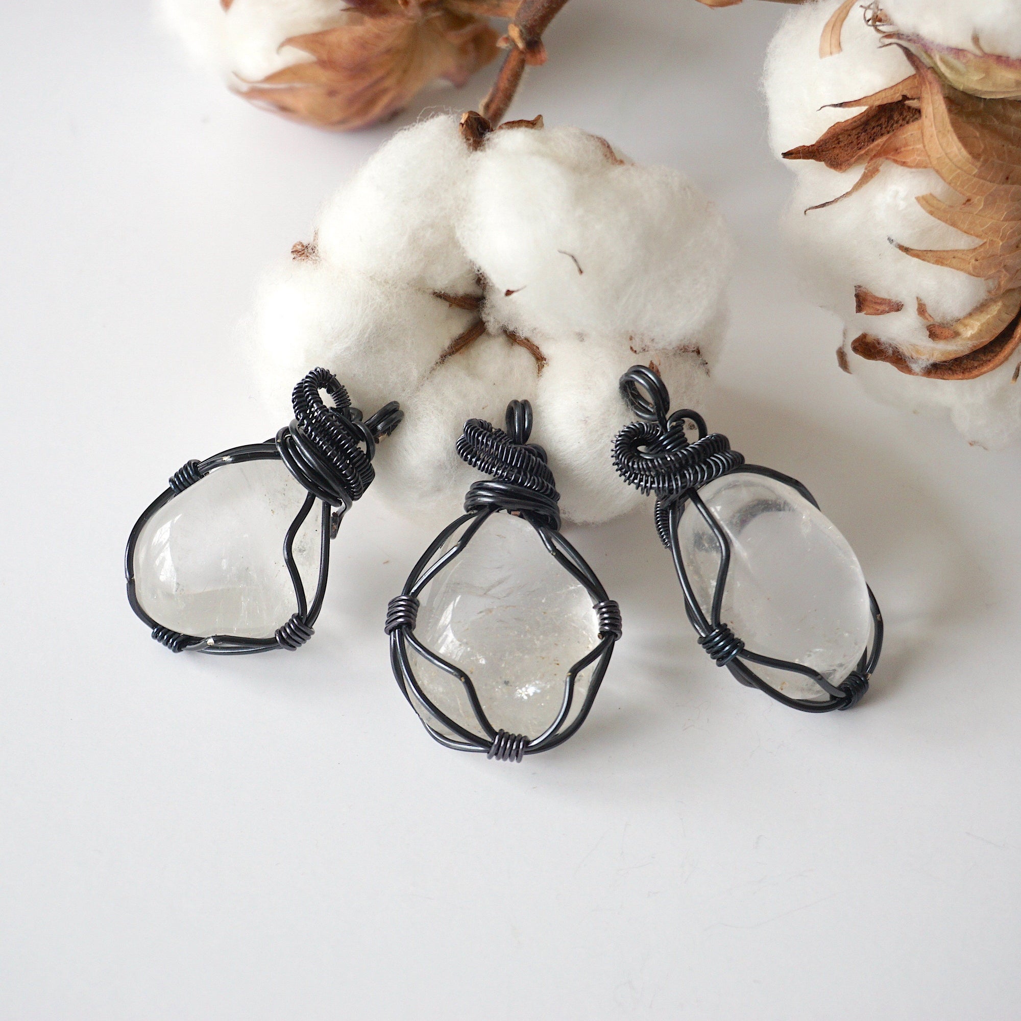 Three clear quartz pendants – showing natural variation in size, shape, gunmetal copper wire wrapping.