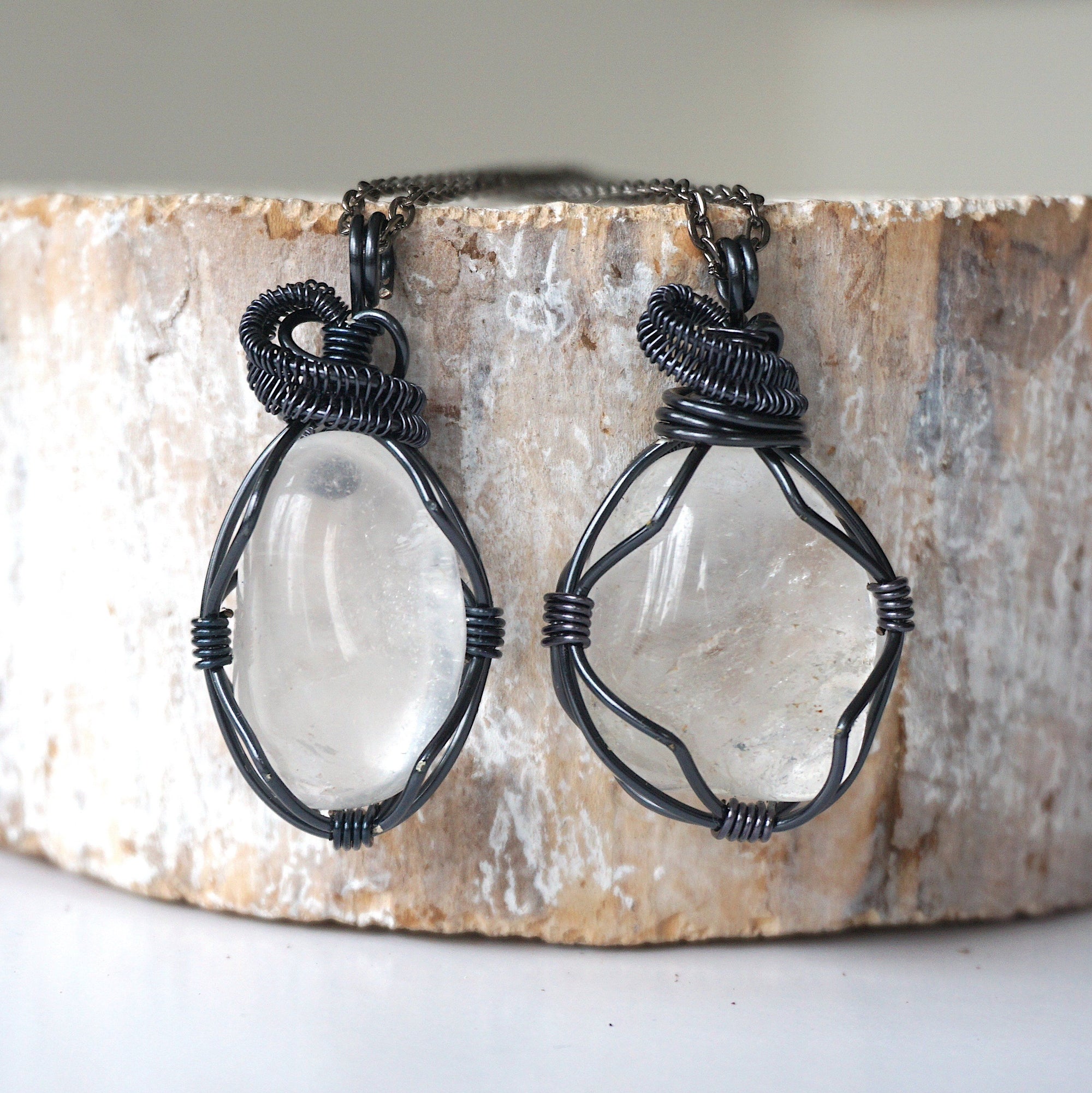 Two clear quartz pendants for men – showing natural variation in size, shape, gunmetal copper wire wrapping.