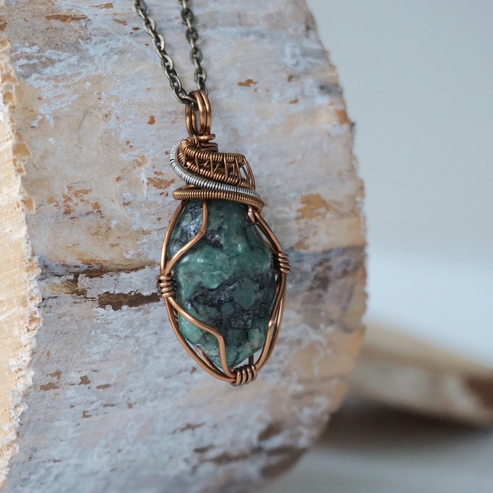 Right angle close-up of emerald necklace – detailed artisan wire wrapping in bronze and silver copper, handcrafted May birthstone pendant.