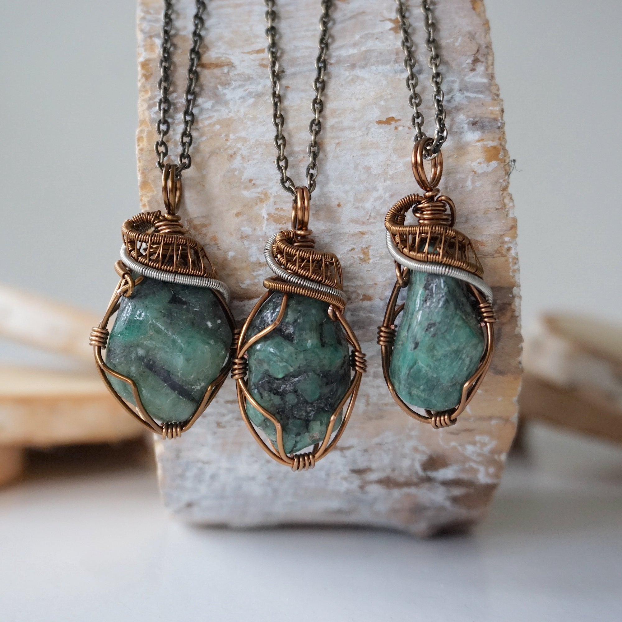 Three raw emerald pendants – showcasing natural variation in size, shape, and green shade, handcrafted unisex birthstone jewelry.