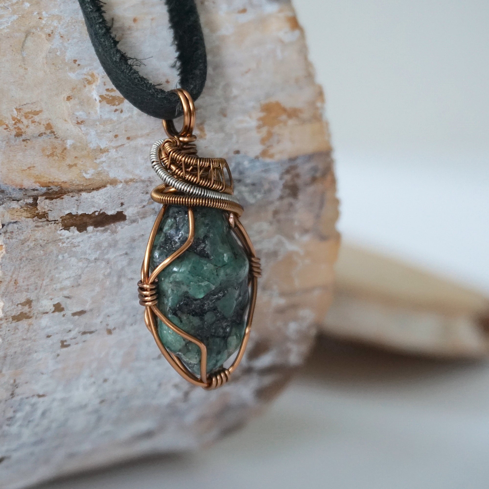 Right angle close-up of men's emerald necklace – detailed bronze and silver copper wire wrapping, black leather cord.