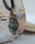 Right angle close-up of men's emerald necklace – detailed bronze and silver copper wire wrapping, black leather cord.