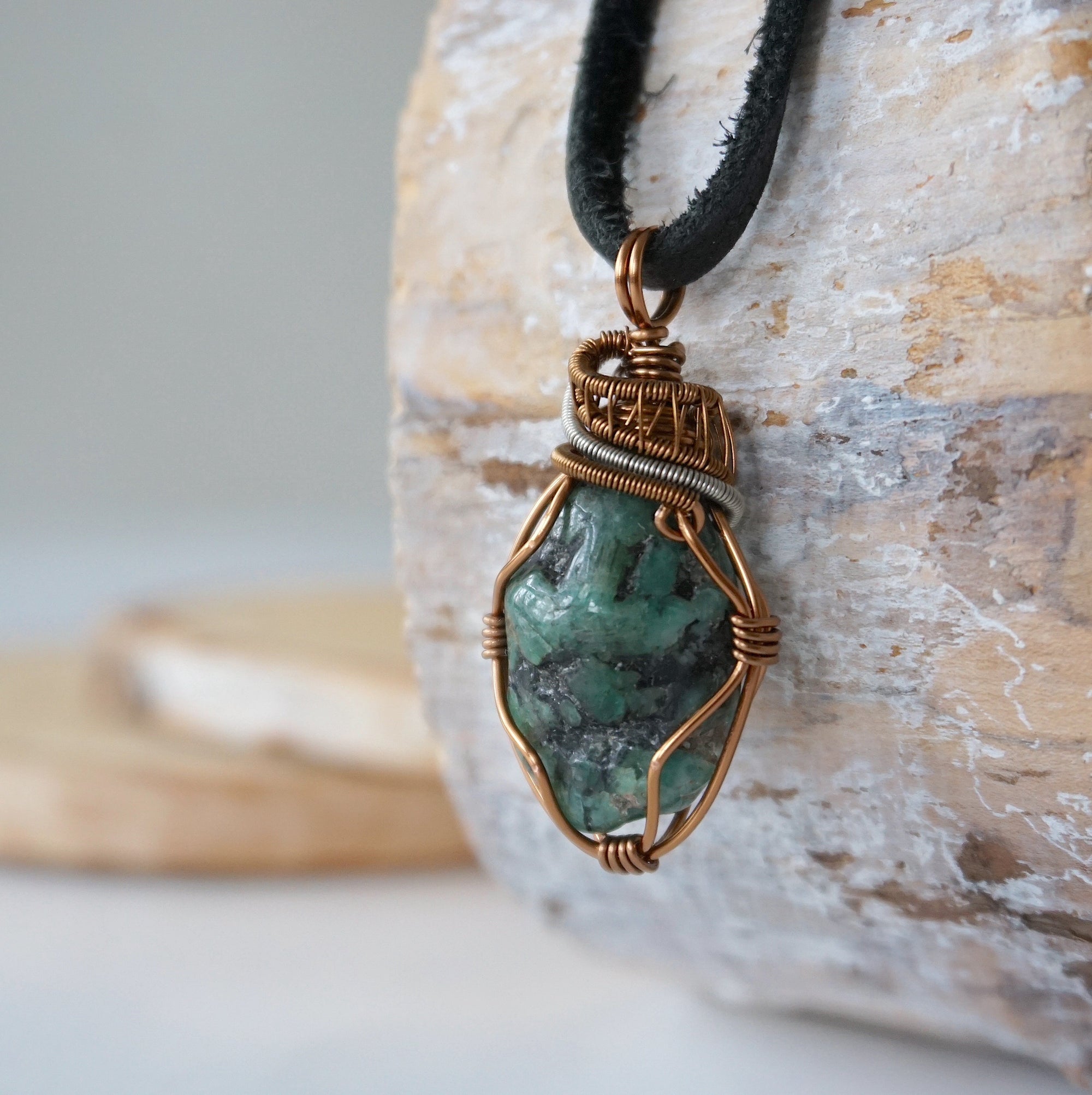 Left angle close-up of men's emerald necklace – highlighting unique wire-wrapped artistry, raw emerald, black leather cord.