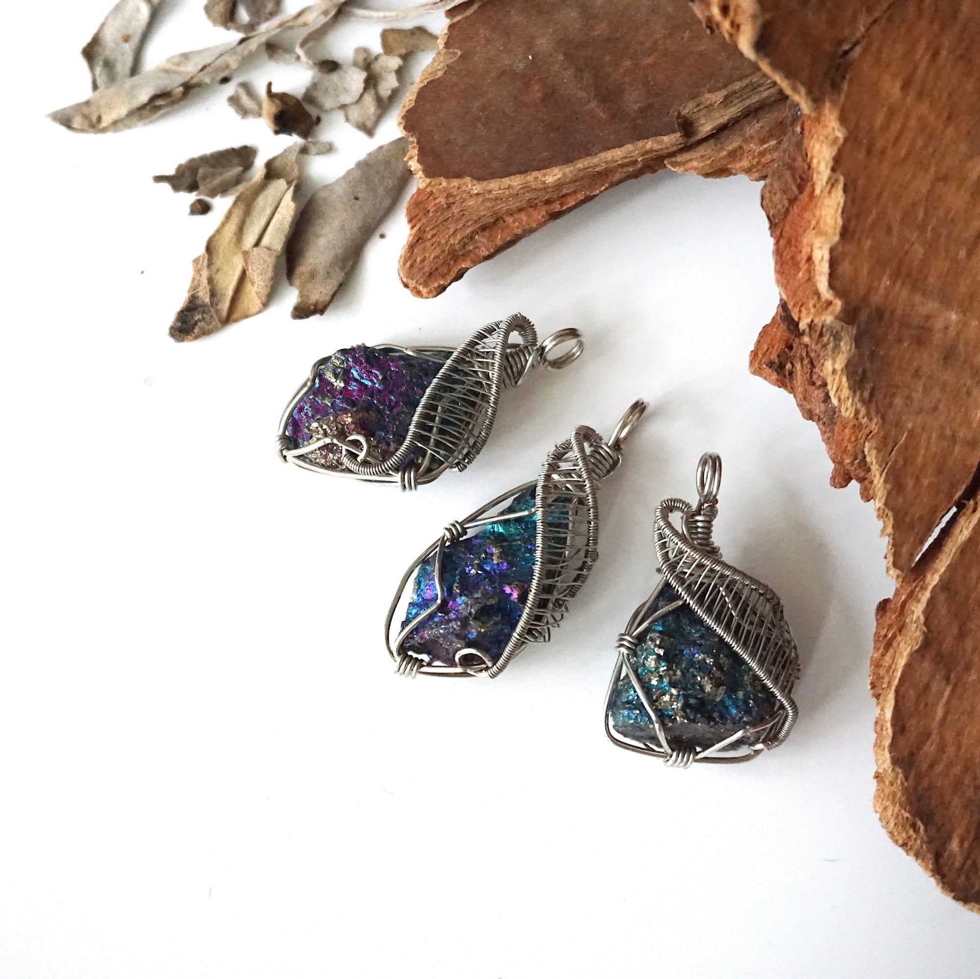 Three peacock ore pendants for men – showing natural variation in size, shape, and iridescent colours, white gold copper wire wrapping.