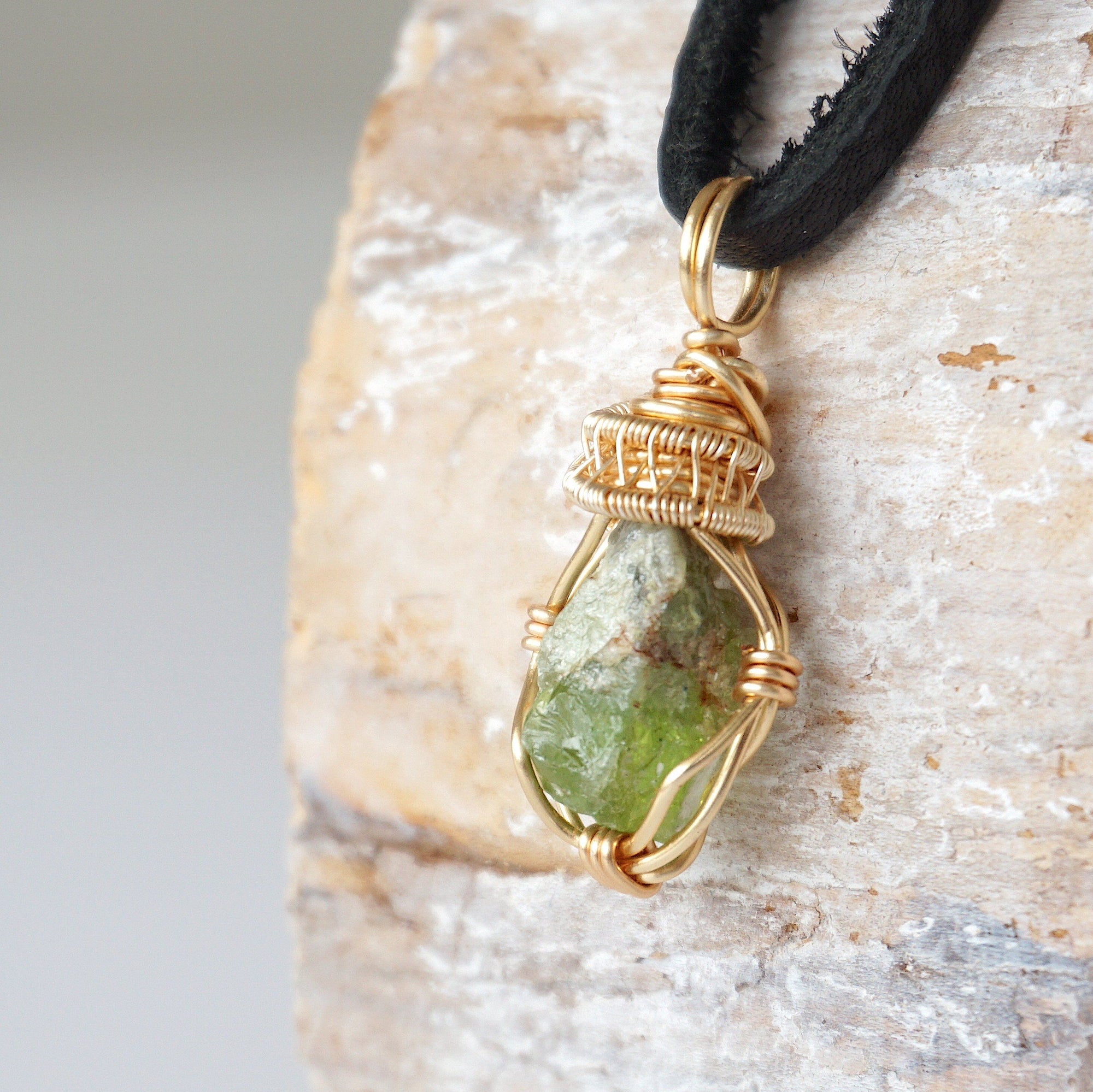 Left angle detail of raw peridot necklace for men – close-up of wire wrapping and vivid green peridot.