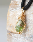 Left angle detail of raw peridot necklace for men – close-up of wire wrapping and vivid green peridot.