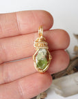 Raw peridot necklace for women in hand – size reference, showcases natural green peridot and gold copper wire wrapping.