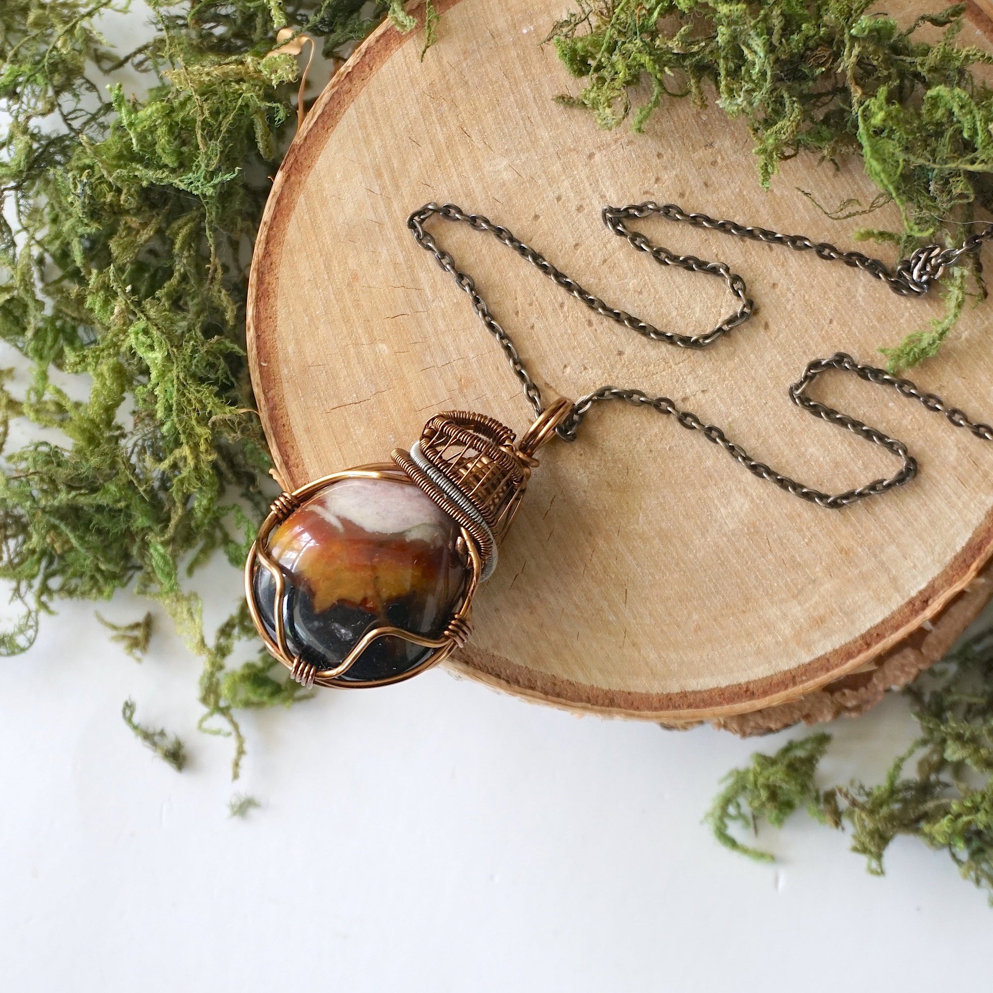 Handcrafted raw sardonyx necklace laying flat – artisan bronze and dark silver copper wire wrapping, August birthstone jewelry for all genders, Designs by Nature Gems.
