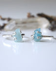 Two adjustable aquamarine rings side by side, showing natural variation in aquamarine's size, shape, and color, 925 sterling silver