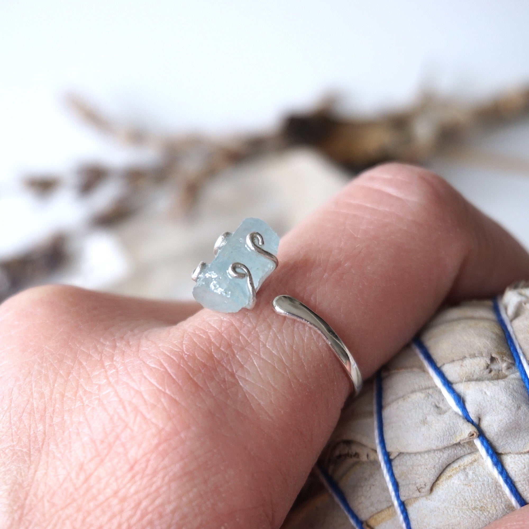 Adjustable aquamarine ring with raw gemstone in 925 sterling silver prong setting on female model's hand, Designs by Nature Gems