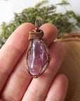 Women’s amethyst necklace in hand for size reference, lighter violet amethyst, antique bronze copper wire wrap