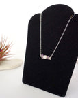 Left angle view of amethyst and pearl bar necklace in 925 sterling silver on jewelry display