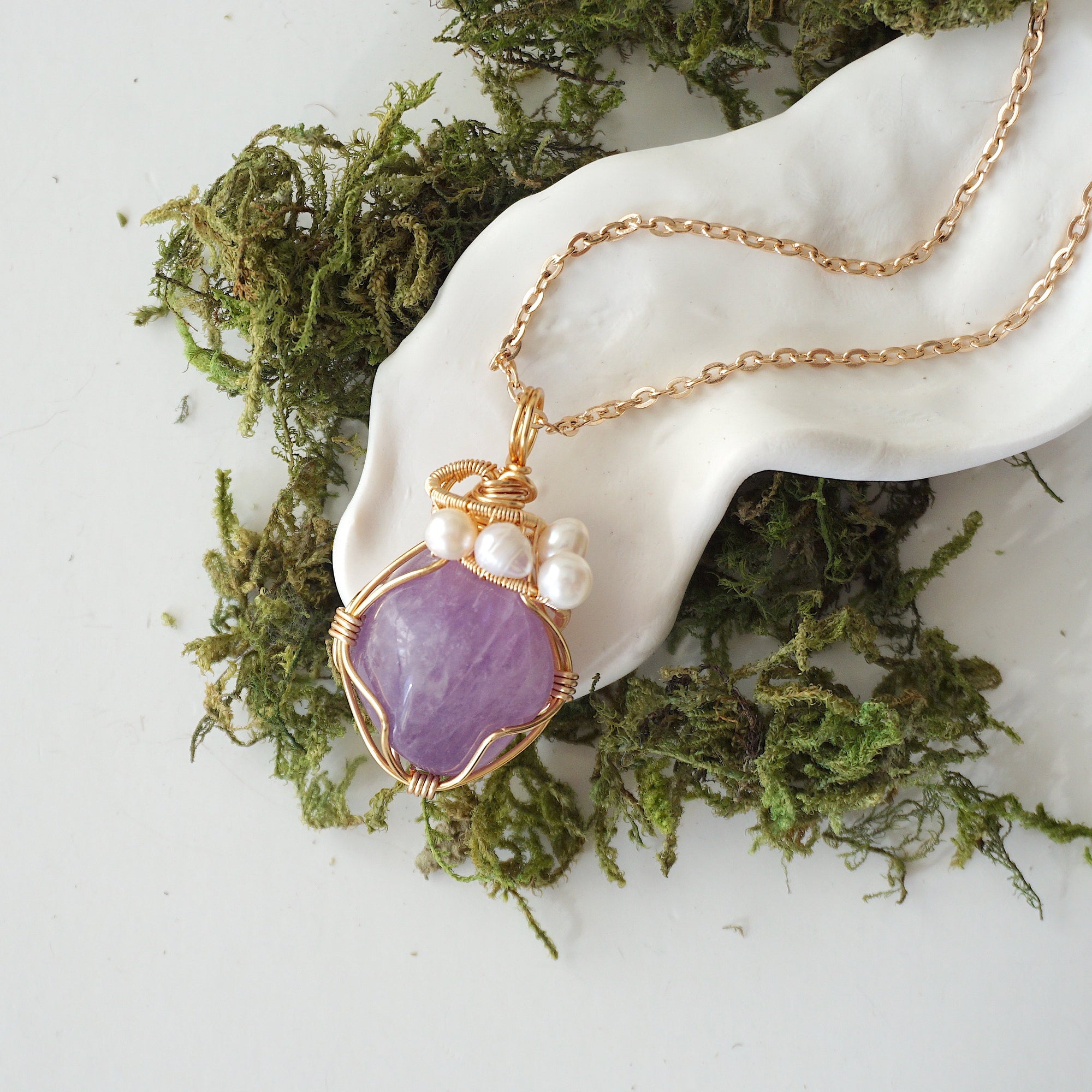 Amethyst and freshwater pearl pendant on gold plated brass chain laying flat, handmade wire wrapped jewelry for women