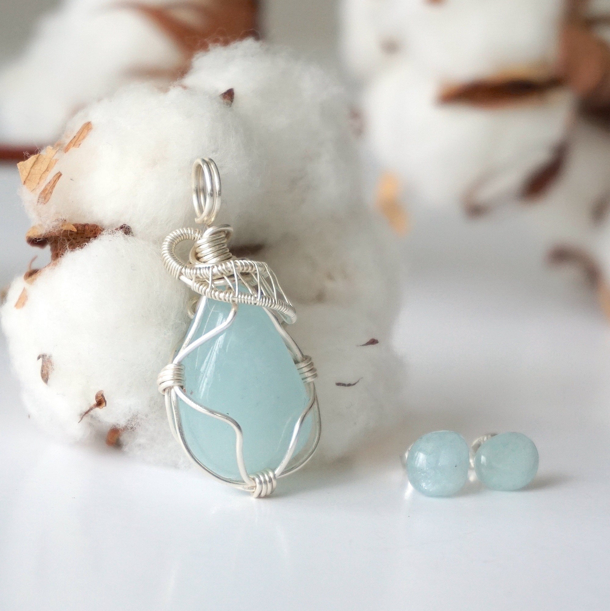 Detailed side angle of aquamarine jewelry set, artisan wire wrapped necklace and raw aquamarine stud earrings, soft silver finish