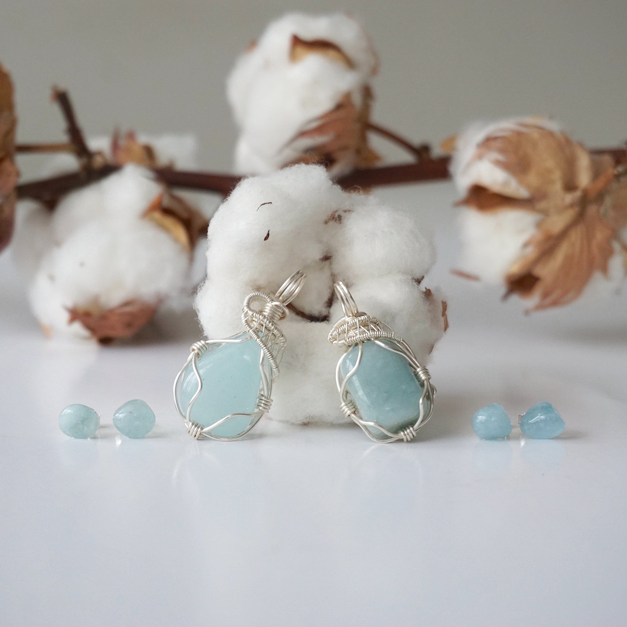 Two aquamarine jewelry sets showing natural variation in aquamarine's color, size, and shape, wire wrapped pendant and stud earrings, Designs by Nature Gems