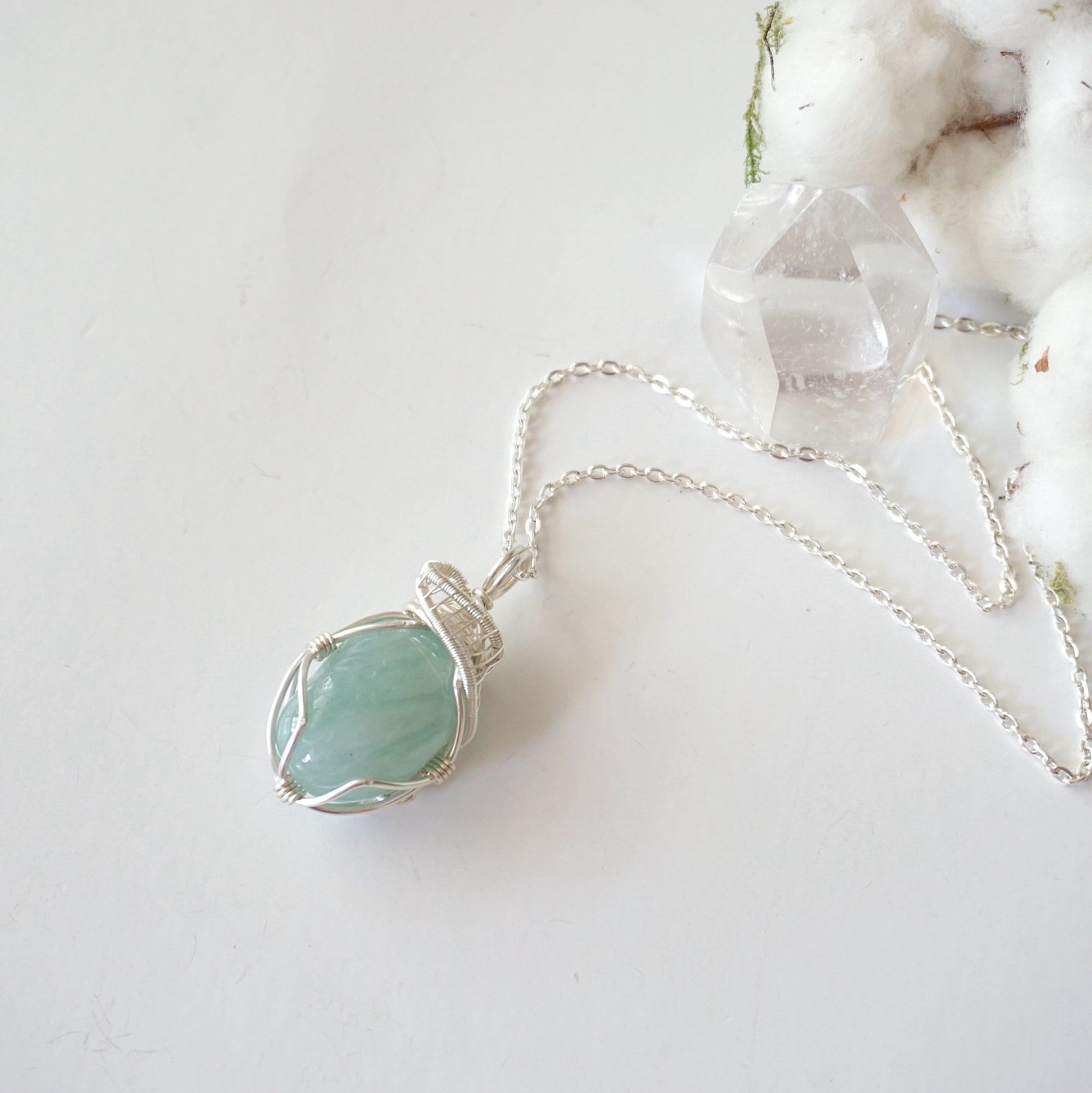 Aquamarine pendant necklace for women on a silver chain laying flat, artisan wire wrapped, soft silver over copper, Designs by Nature Gems