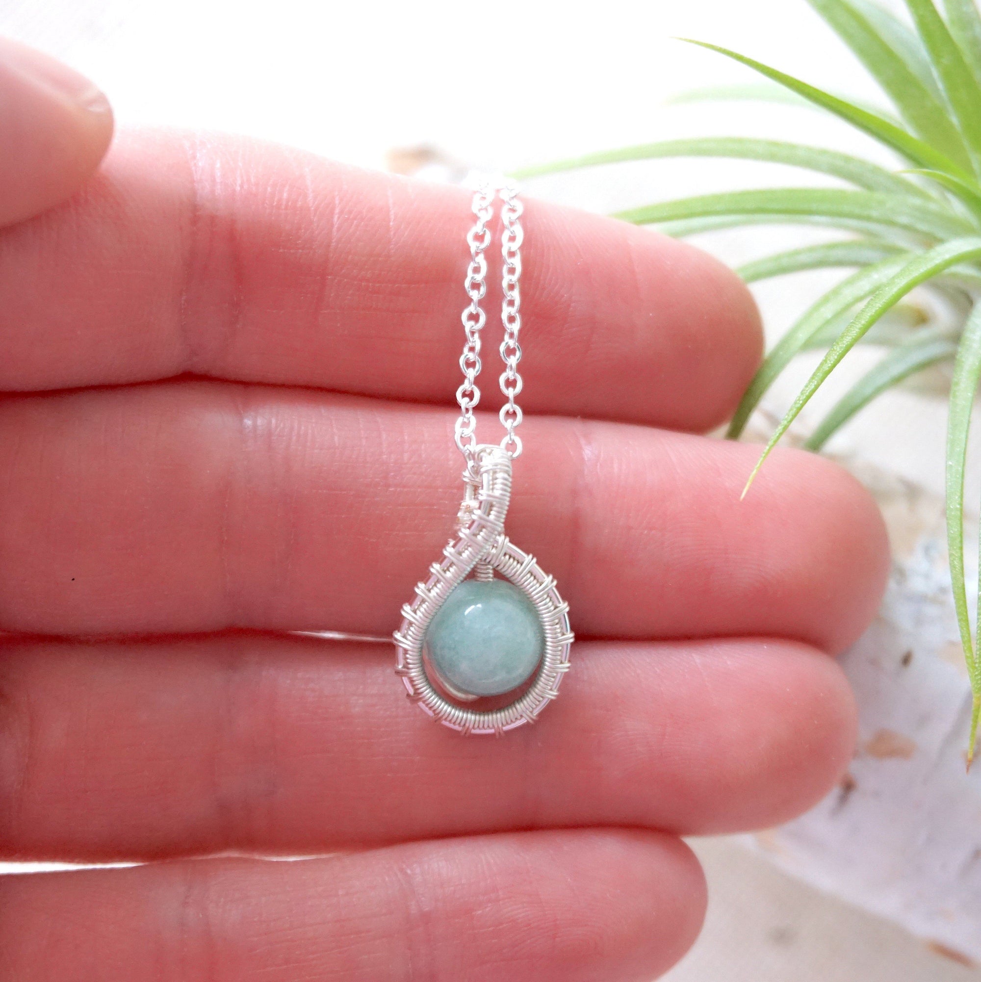 Aquamarine necklace in hand for size reference, genuine aquamarine bead, soft silver finish wire wrapping