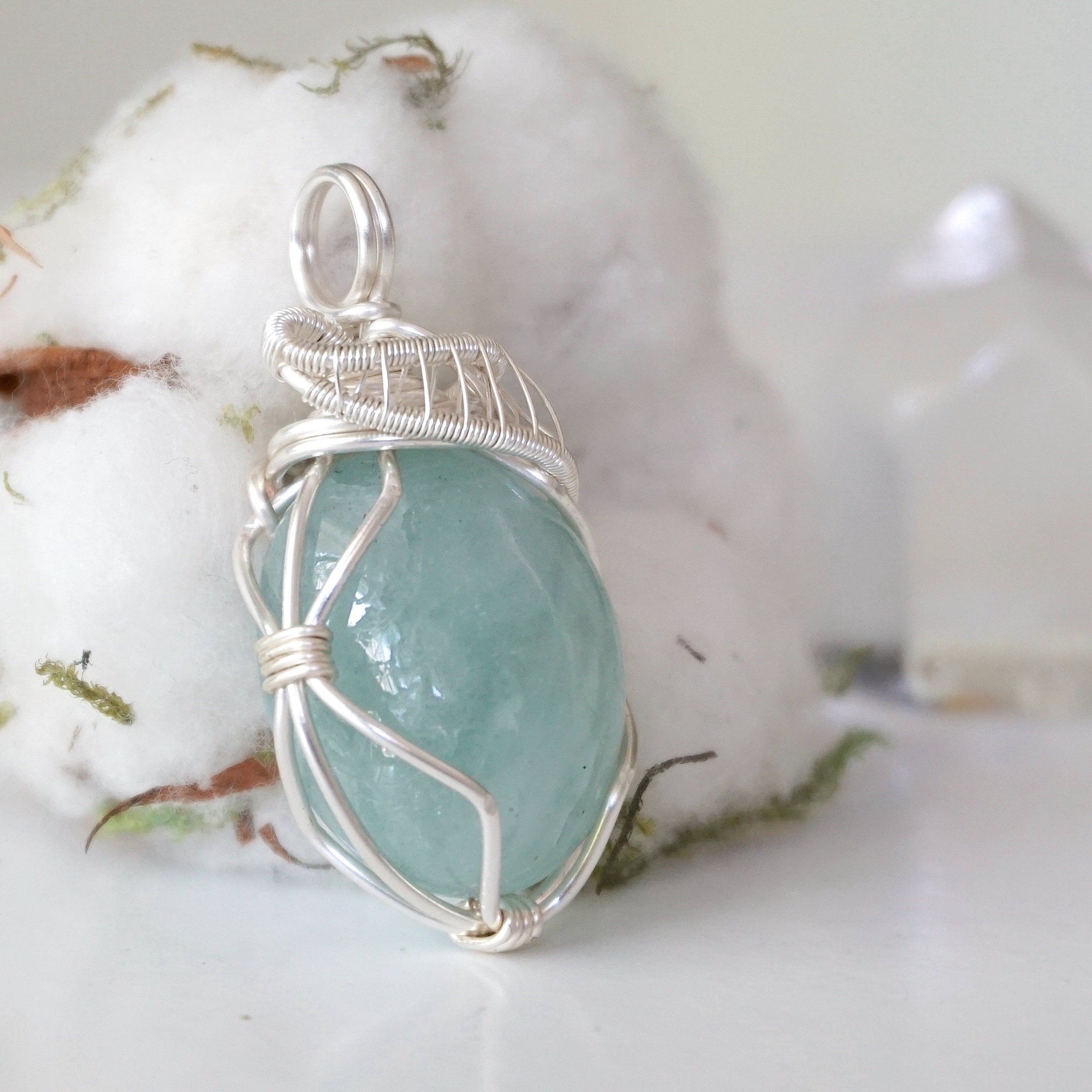 Side angle of aquamarine pendant showing artisan wire wrapping details, soft silver over copper