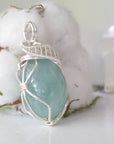 Side angle of aquamarine pendant showing artisan wire wrapping details, soft silver over copper