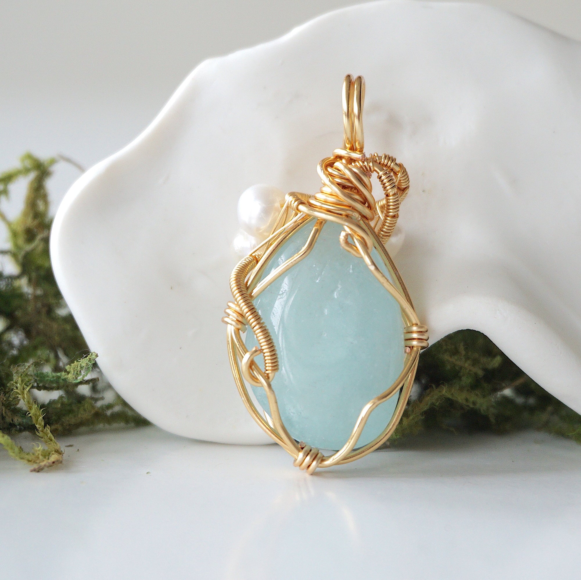 Back angle detail of aquamarine and freshwater pearl pendant, showing wire wrapping and natural stone