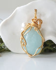 Back angle detail of aquamarine and freshwater pearl pendant, showing wire wrapping and natural stone