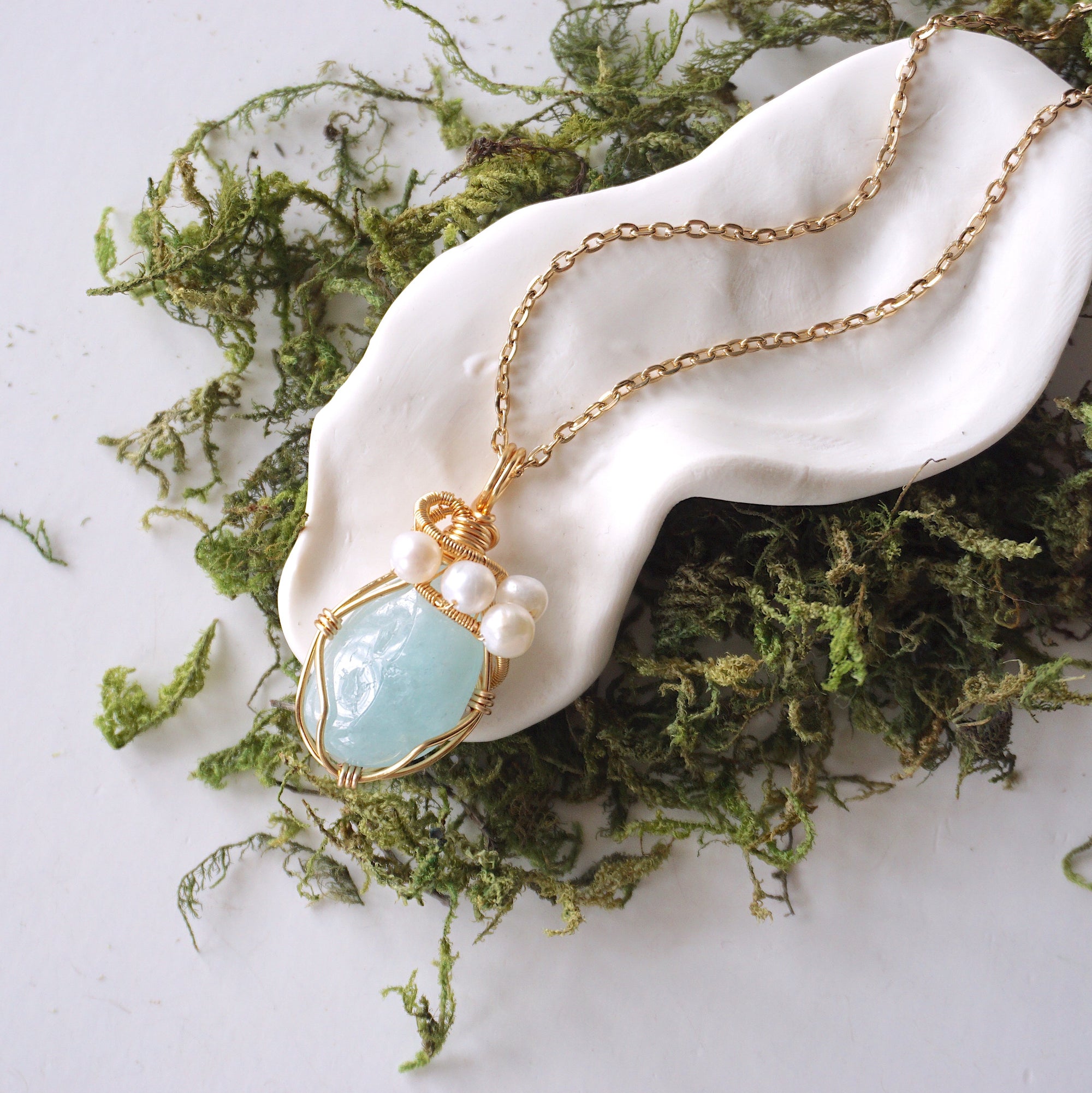 Aquamarine and freshwater pearl pendant on gold plated brass chain laying flat, handmade wire wrapped jewelry for women