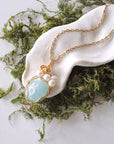 Aquamarine and freshwater pearl pendant on gold plated brass chain laying flat, handmade wire wrapped jewelry for women