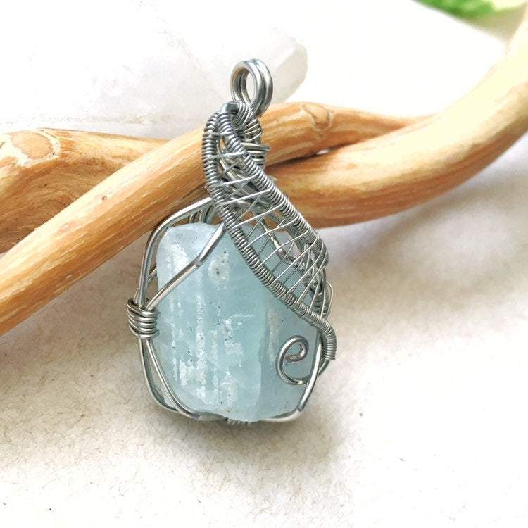 Close-up of aquamarine pendant front, raw gemstone in detailed artisan dark silver wire wrapping