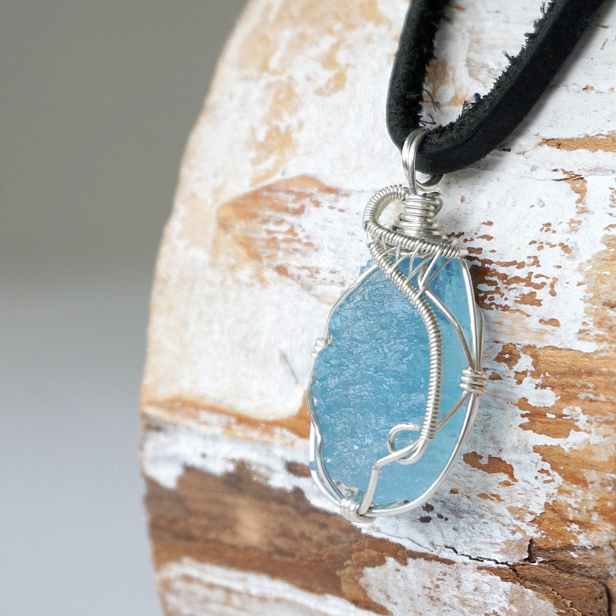Left side view of raw aquamarine pendant showing detailed artisan wire wrapping in sterling silver, men's design