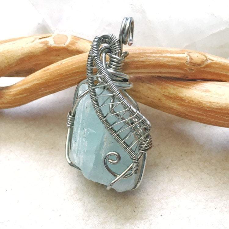 Side view of raw aquamarine pendant showing detailed artisan wire wrapping in dark silver