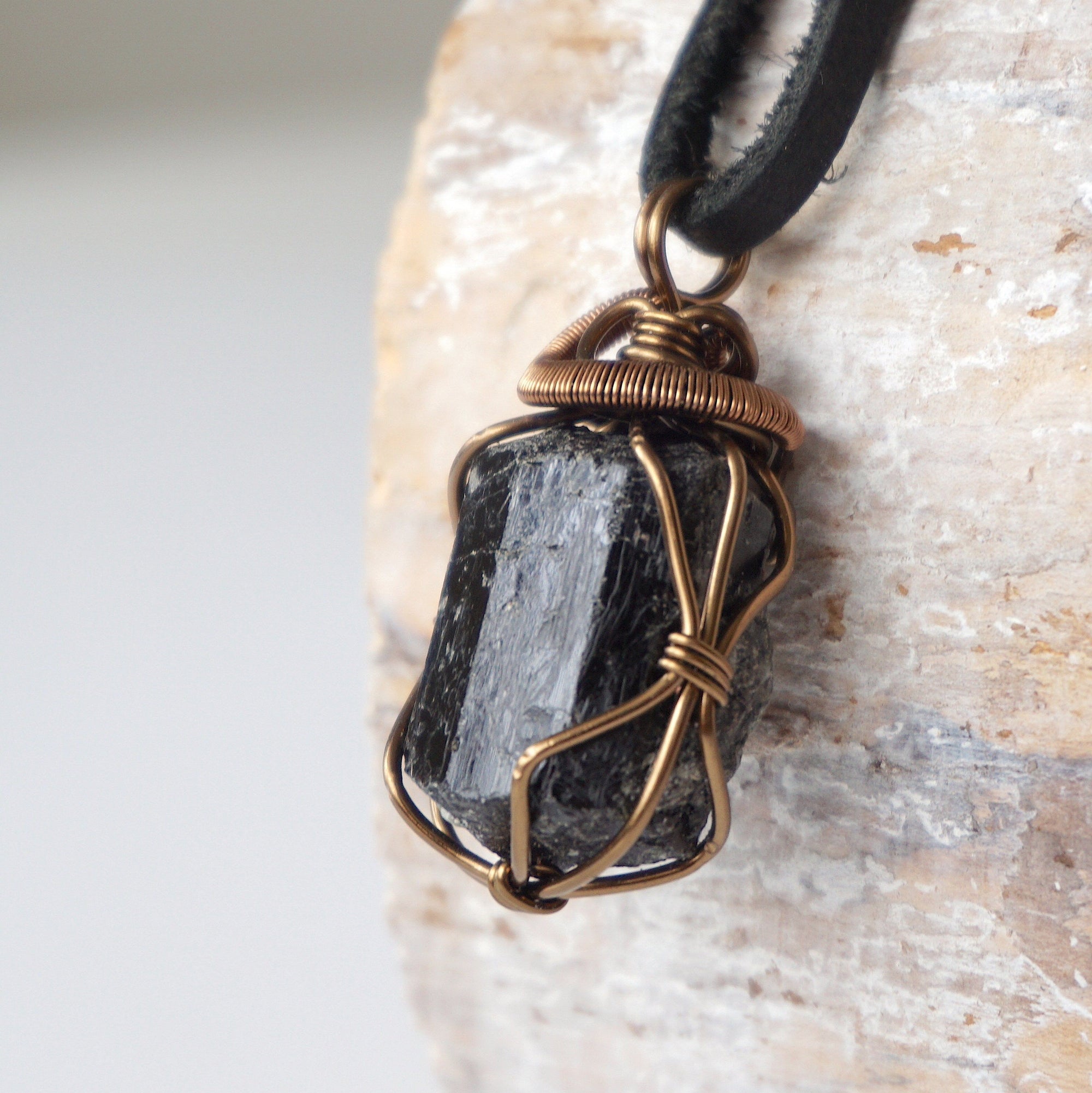 Left side angle detail of raw black tourmaline necklace on black leather cord, wire wrapped pendant by Designs by Nature Gems.
