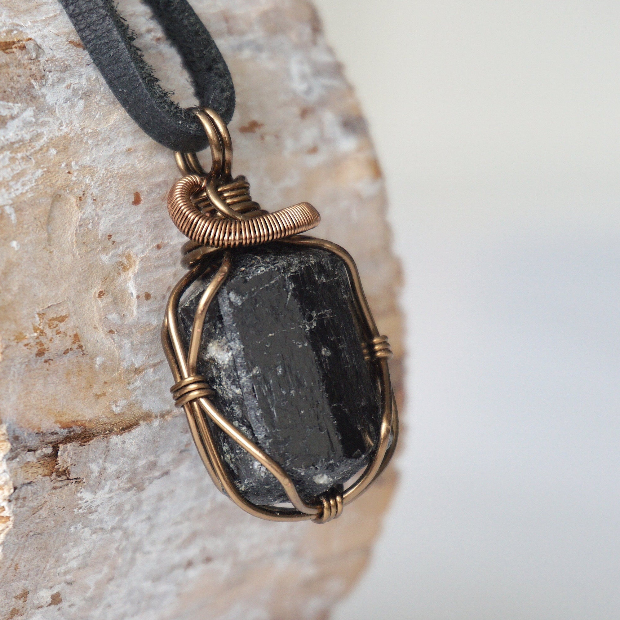 Right side angle detail of raw black tourmaline necklace on black leather cord, wire wrapped pendant by Designs by Nature Gems.