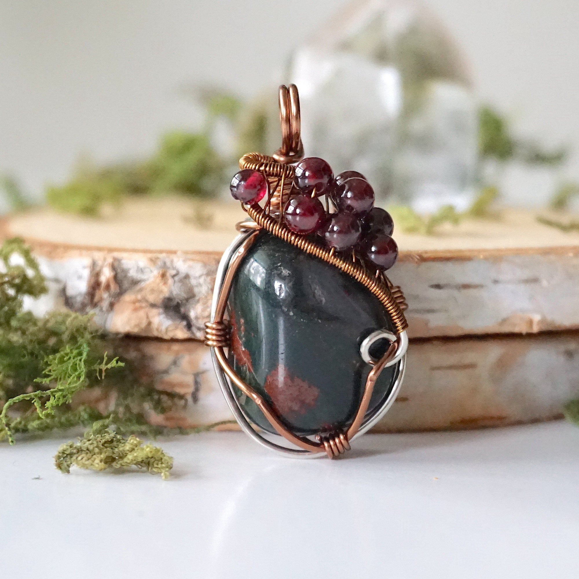 Detailed front view of a bloodstone pendant necklace with garnet accent beads and wire wrapped design