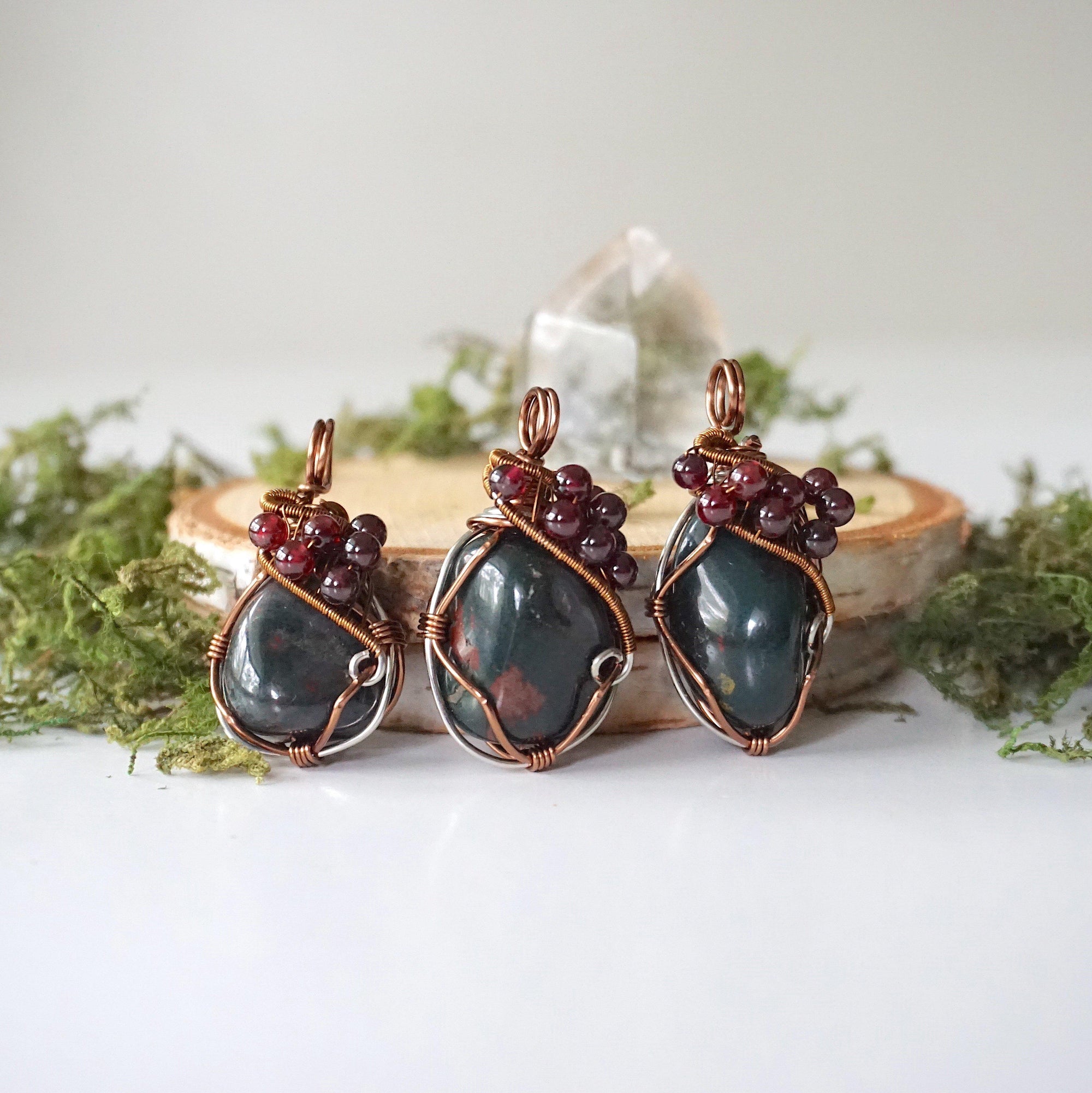 Three bloodstone and garnet pendants showing natural variation in size and stone shape