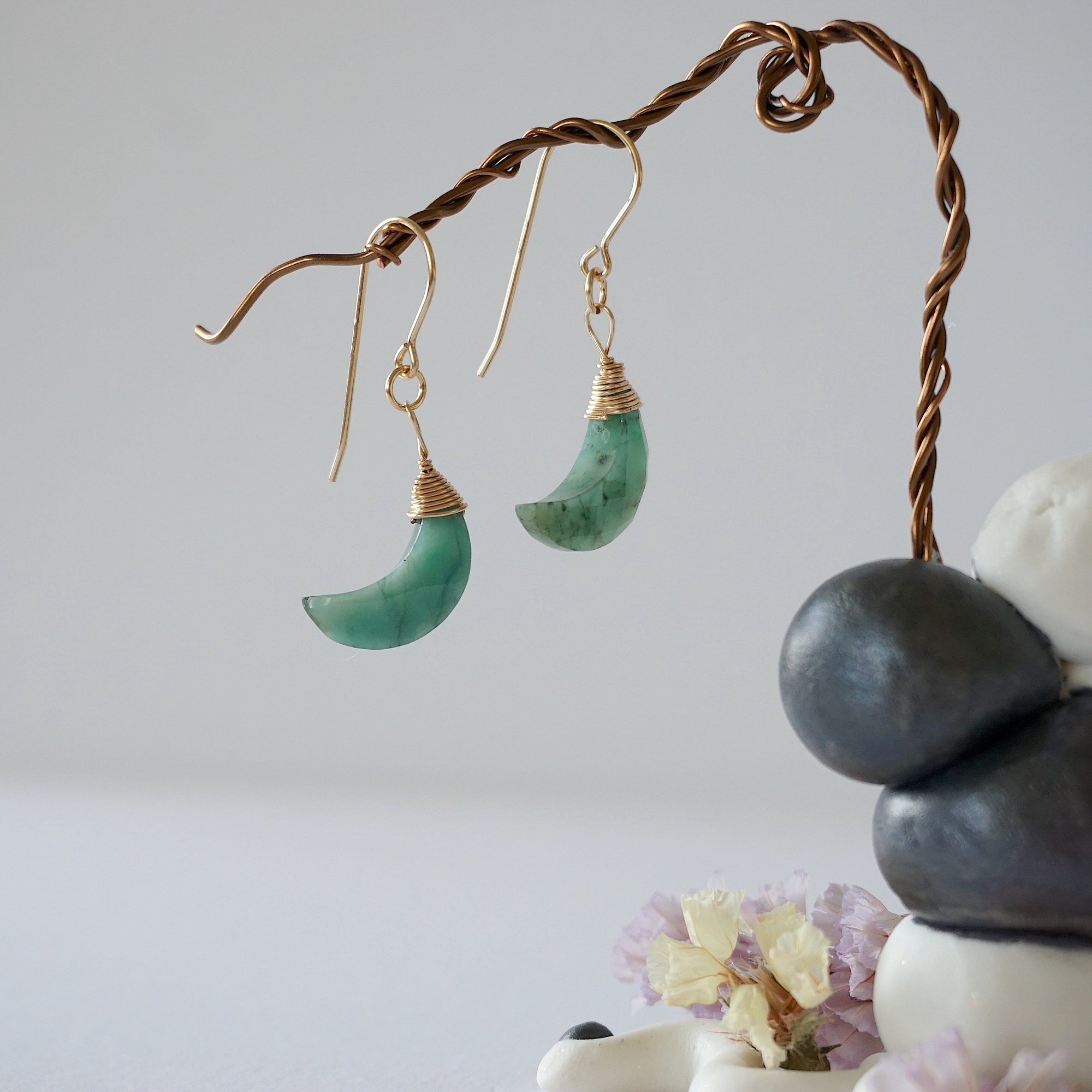 Side angle view of emerald moon drop earrings showing 14k gold filled artisan wire wrapping and faceted emerald detail.