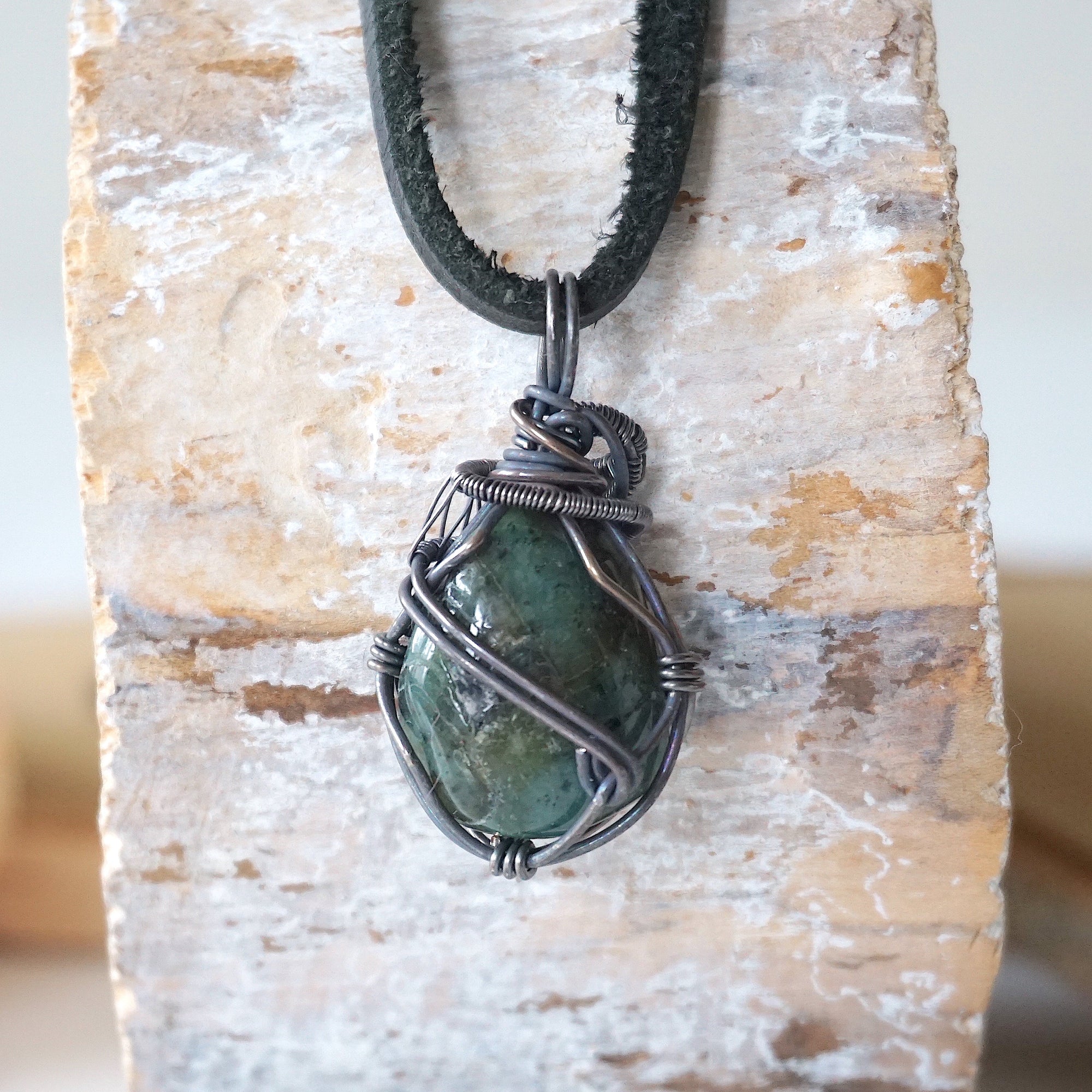 Back angle view of emerald necklace for men with natural polished-raw emerald and detailed antiqued sterling silver craftsmanship